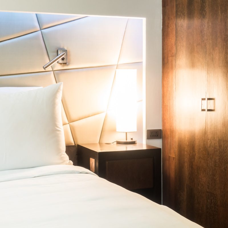 Beautiful white pillow on bed with table light lamp decoration in bedroom interior